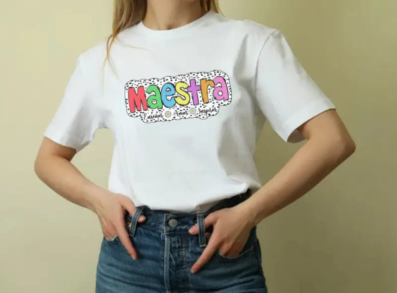 White t-shirt with colorful ’Maestra’ text graphic design.